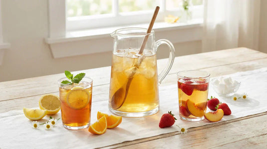 A bright spring table setting featuring a clear pitcher of iced tea and two glasses of different iced tea styles with fresh fruit.
