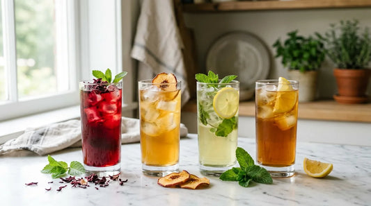 Four tall glasses of iced tea — hibiscus, peach, mint green, and black tea — arranged on a marble surface with fresh garnishes for a food pairing guide