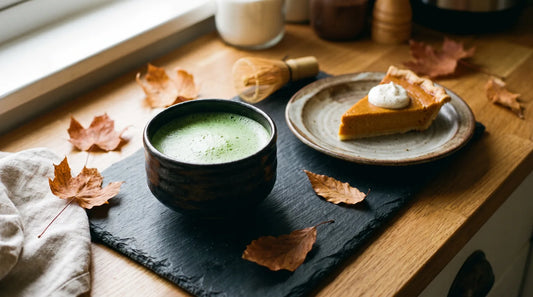 Best tea for fall desserts: ceremonial matcha in a chawan beside a slice of pumpkin pie and autumn leaves on dark slate