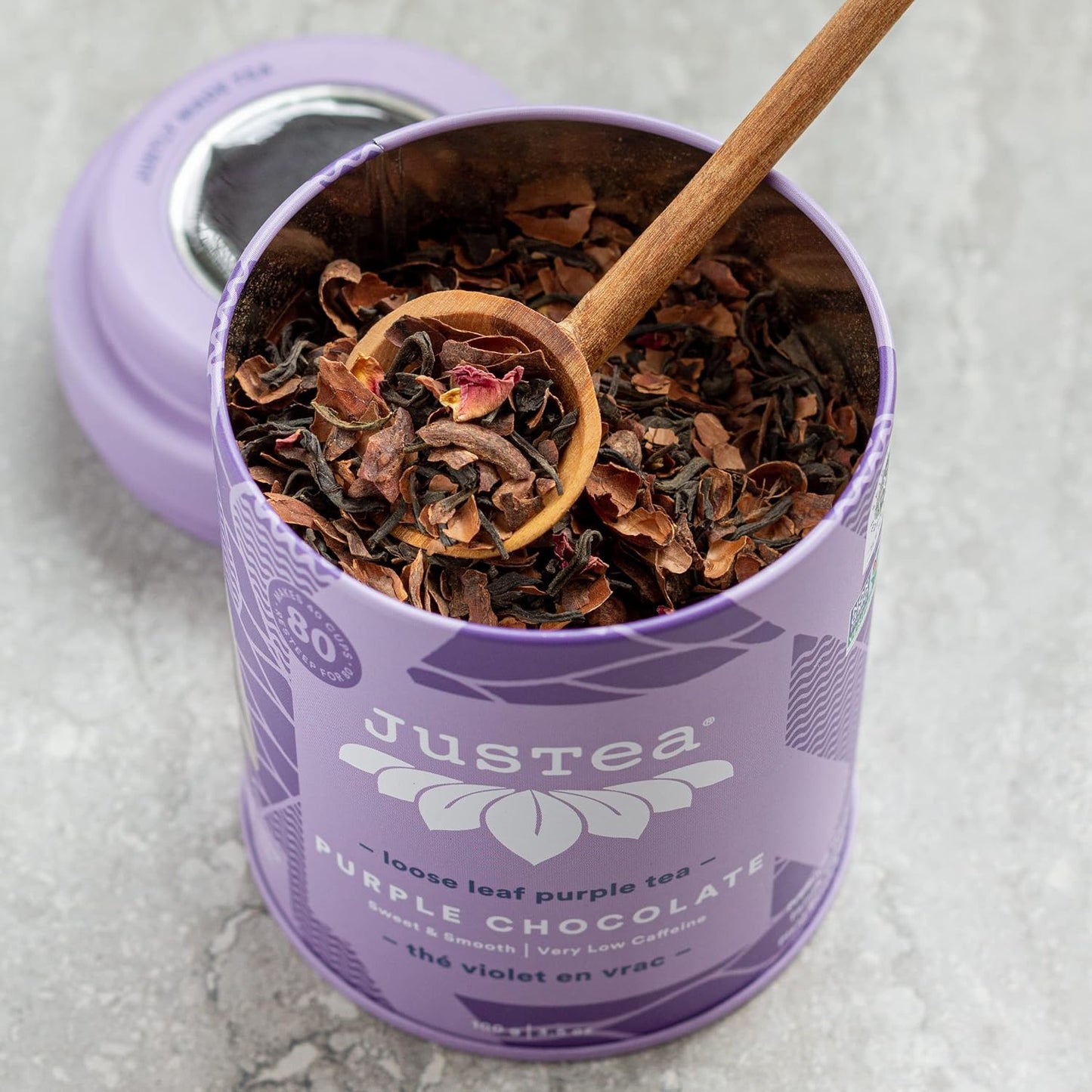 JusTea PURPLE CHOCOLATE Loose Purple Tea, 40+ Cup Tin + Spoon, 1/5 Caffeine | Fair-Trade PURPLE CHOCOLATE Loose Leaf Purple Tea. 100g/3.5oz Tin with a Hand-Carved Tea Spoon. 1/5 Caffeine. Organic.